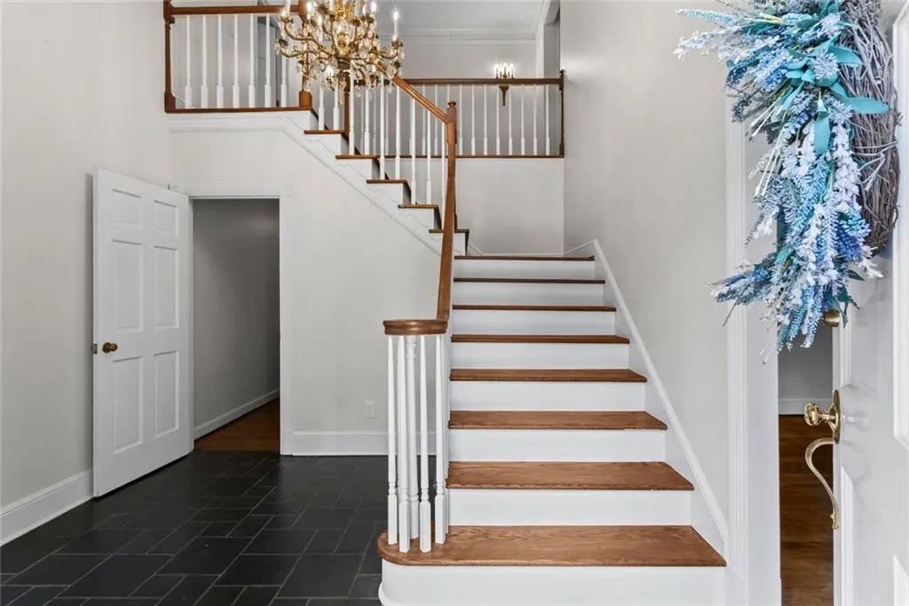 Grand two-story foyer with elegant staircase, timeless chandelier, and natural light.