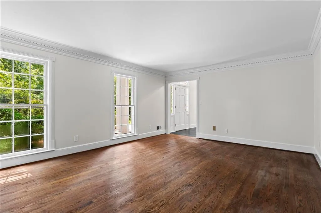 Spacious living room with hardwood floors, large windows, and classic trim details.