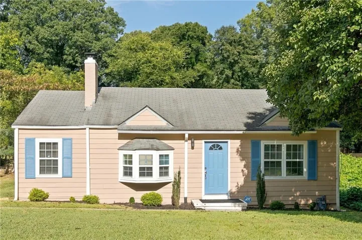 Siding exterior with a light blue entry door, white trim, and a bay window