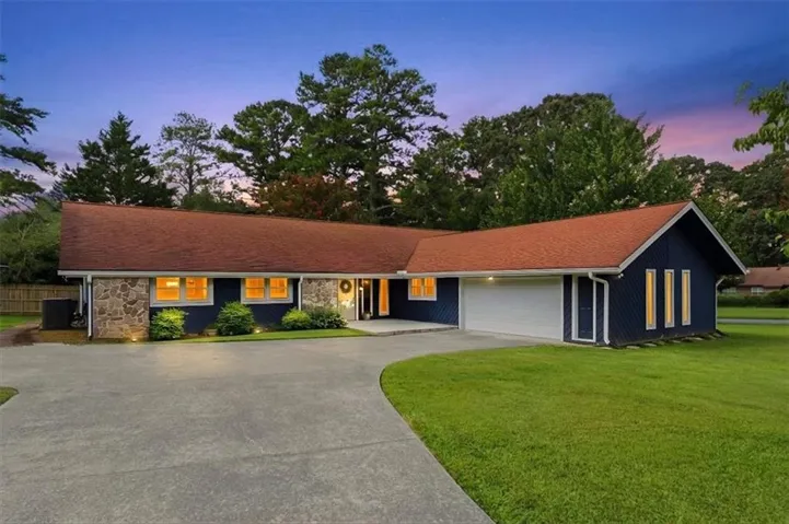 Single-story residence featuring a red-shingle roof, stone and siding exterior, an attached garage, and a concrete driveway