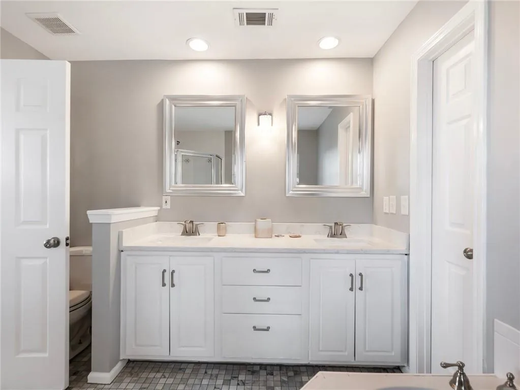 Bathroom featuring dual bowl vanity, tile patterned floors, and toilet