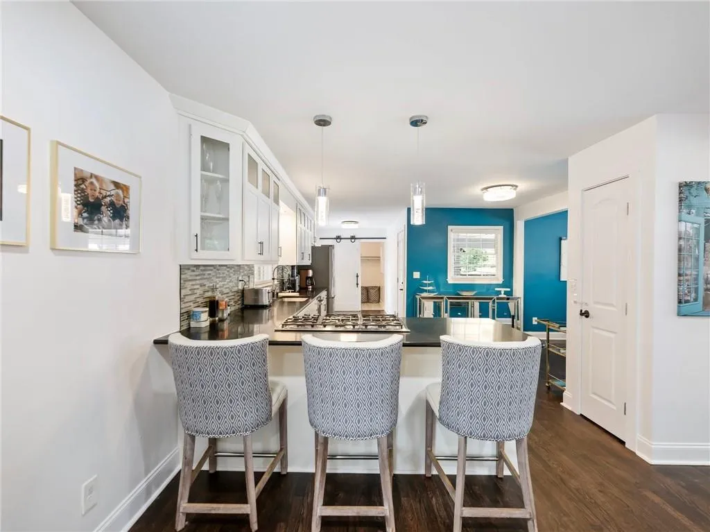 Kitchen featuring dark wood-type flooring, white cabinets, a kitchen breakfast bar, backsplash, and kitchen peninsula
