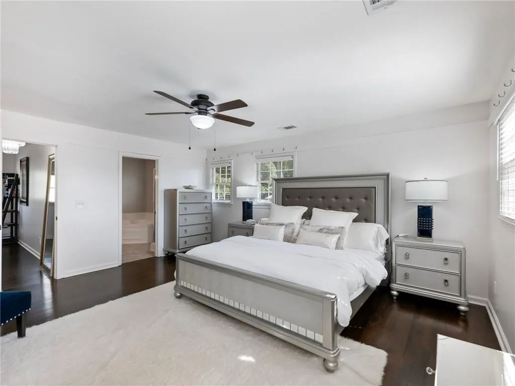 Bedroom with ceiling fan, ensuite bath, and dark wood-type flooring