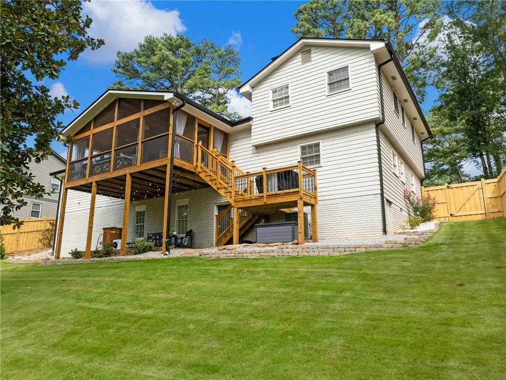 Rear view of property with a sunroom, a yard, and a deck