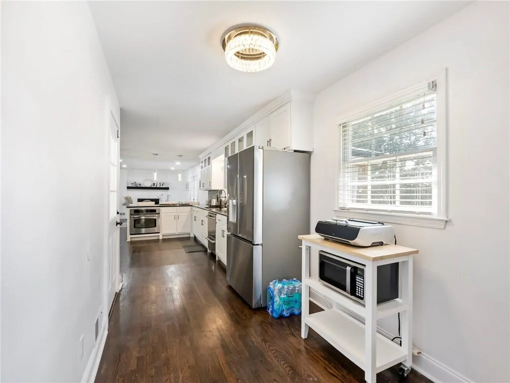 Kitchen with appliances with stainless steel finishes, backsplash, dark hardwood / wood-style floors, and white cabinetry
