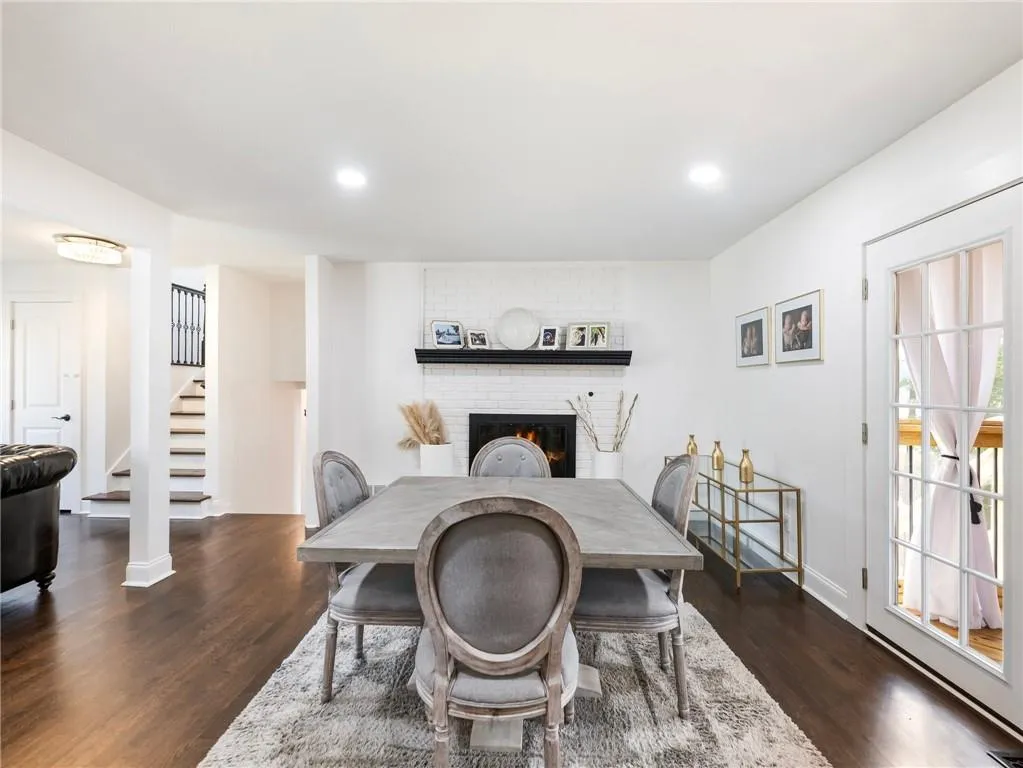 Dining room featuring ornate columns, dark wood-type flooring, a fireplace, and brick wall