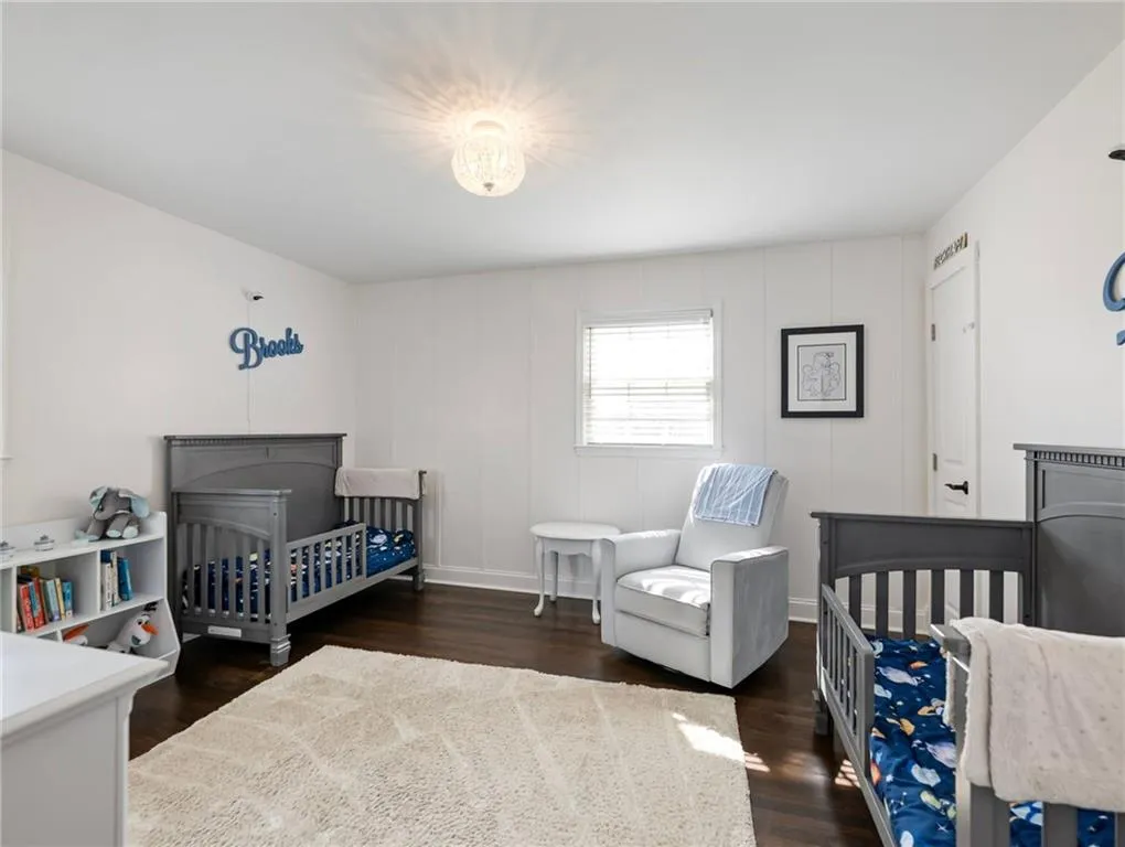 Bedroom featuring a crib and dark wood-type flooring