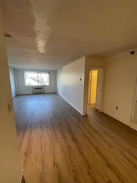 Spare room featuring a textured ceiling, hardwood / wood-style flooring, and an AC wall unit