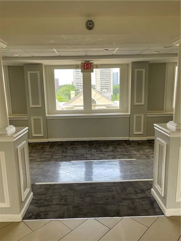 Tiled spare room featuring a healthy amount of sunlight and decorative columns