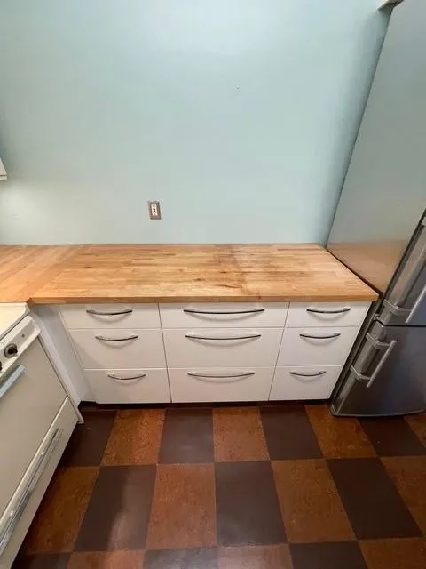 Room details with fridge, wood counters, white cabinetry, and range