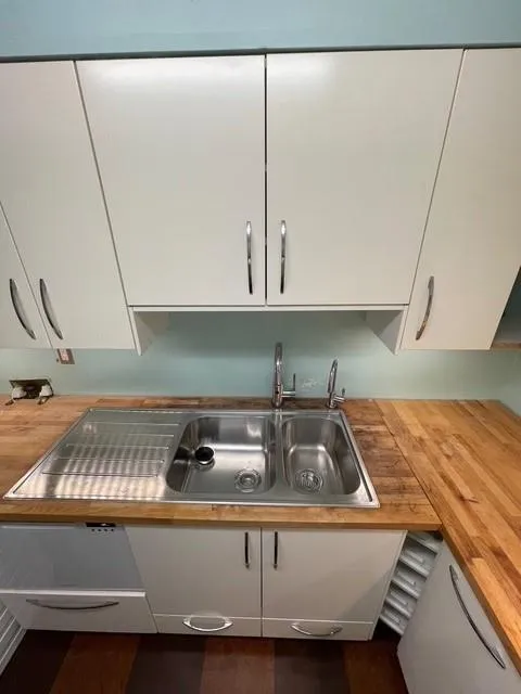 Interior details featuring white cabinets, butcher block counters, and sink