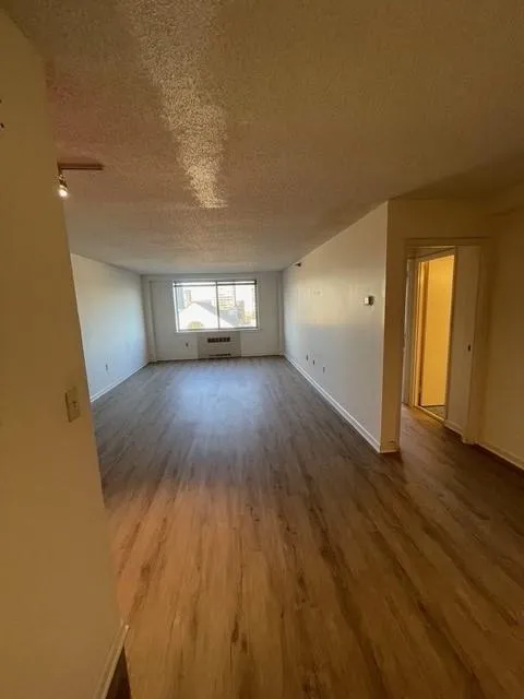 Spare room with hardwood / wood-style flooring, a textured ceiling, and a wall unit AC