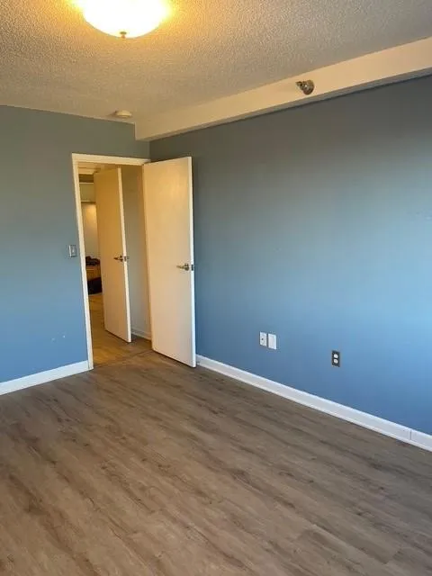 Spare room with a textured ceiling and dark hardwood / wood-style flooring