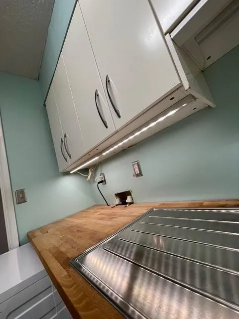 Room details featuring butcher block countertops and white cabinetry