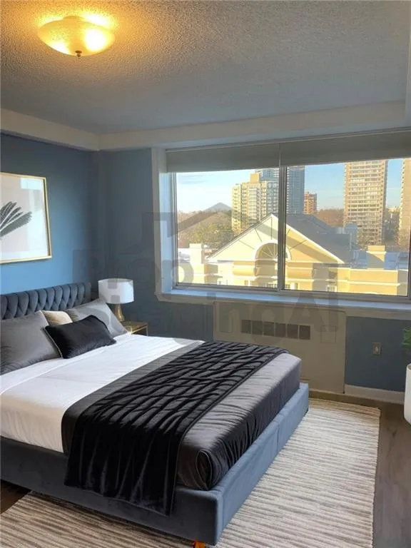 Bedroom featuring multiple windows, a textured ceiling, and wood finished floors.Look at AI Staging what thing could be like with a vision!