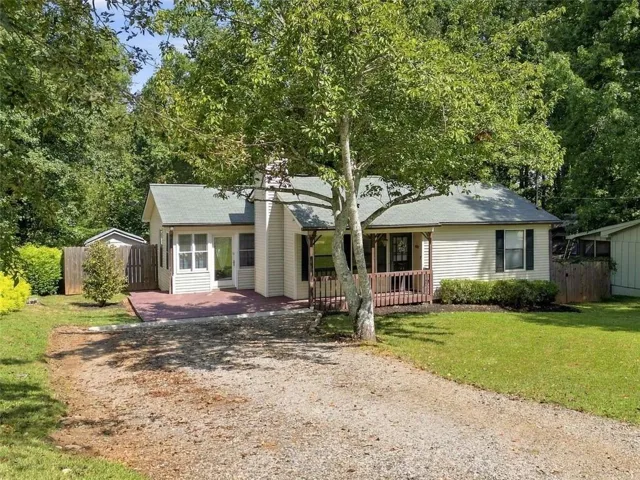 Siding exterior with a covered front porch, gravel driveway, and a detached shed