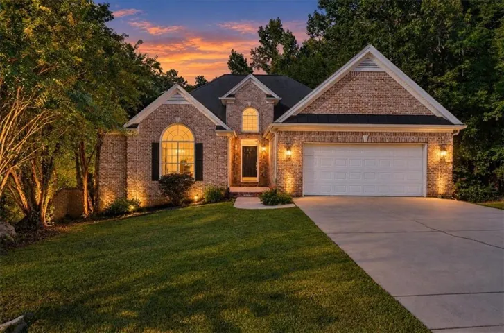 Brick exterior with white trim, arched window, and attached two-car garage