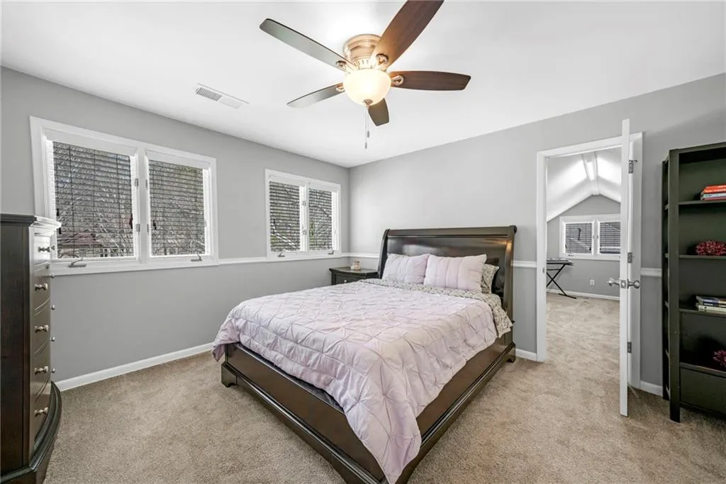 Bedroom featuring ceiling fan, light carpet, and vaulted ceiling