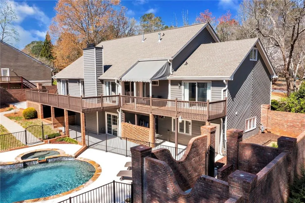 Rear view of house with a patio area, a balcony, and a swimming pool with hot tub