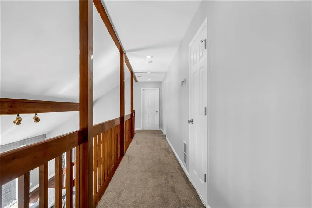 Corridor featuring vaulted ceiling and light carpet