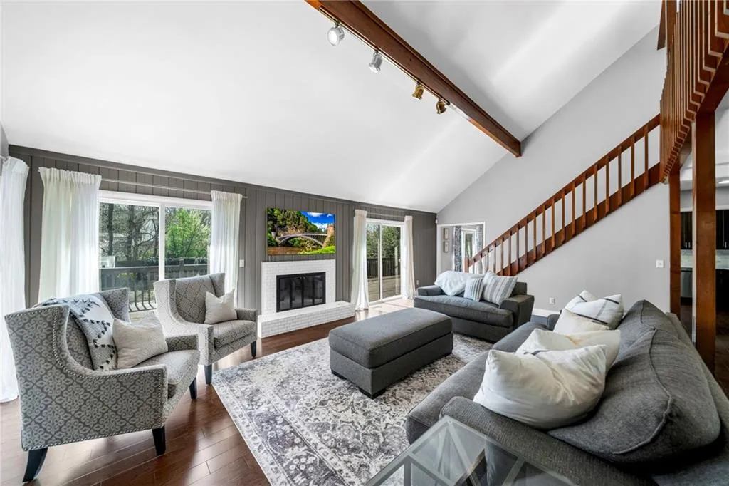 Living room featuring lofted ceiling with beams, dark hardwood / wood-style floors, a fireplace, track lighting, and plenty of natural light