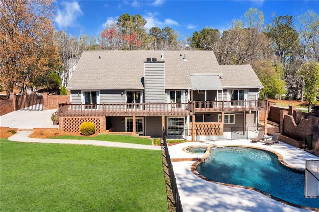 Rear view of house featuring a pool side deck, a patio area, and a lawn