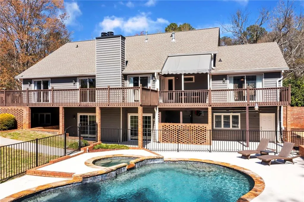 Rear view of property with a swimming pool with hot tub, a balcony, and a patio area