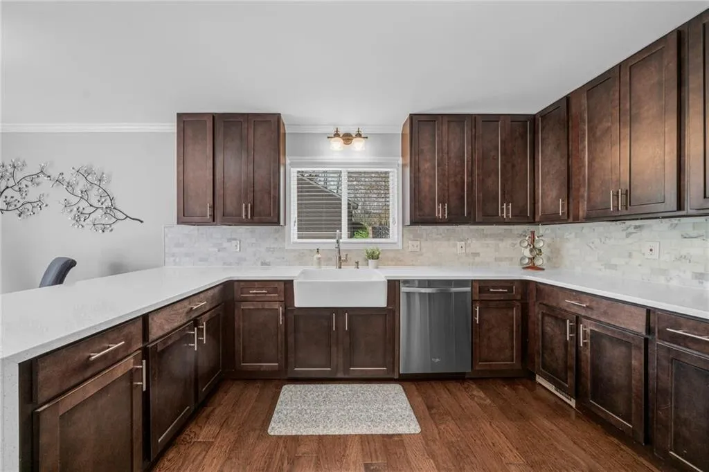 Kitchen with backsplash, dishwasher, sink, and dark wood-type flooring