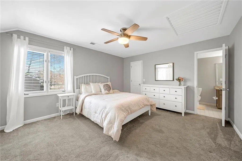 Carpeted bedroom with lofted ceiling, connected bathroom, and ceiling fan