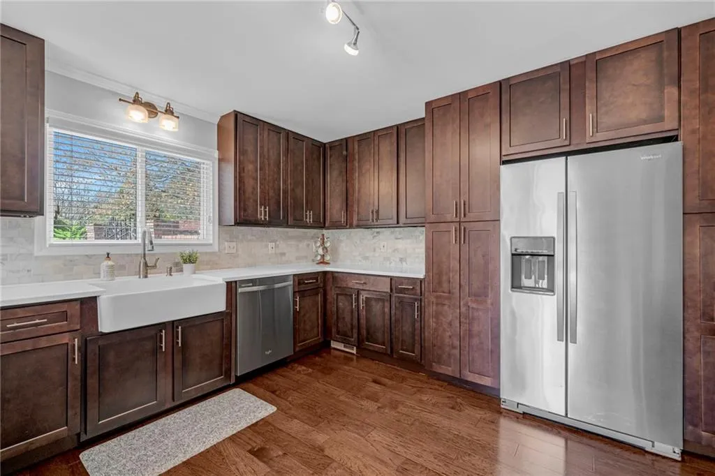 Kitchen featuring dark brown cabinets, stainless steel appliances, track lighting, sink, and dark wood-type flooring