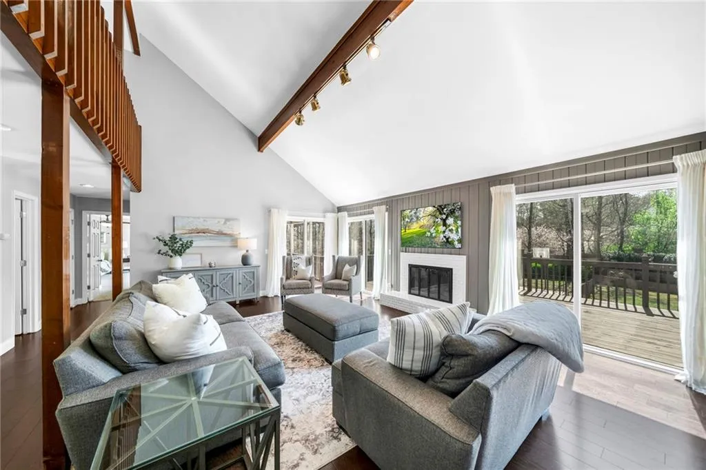 Living room featuring beam ceiling, track lighting, high vaulted ceiling, and dark hardwood / wood-style floors