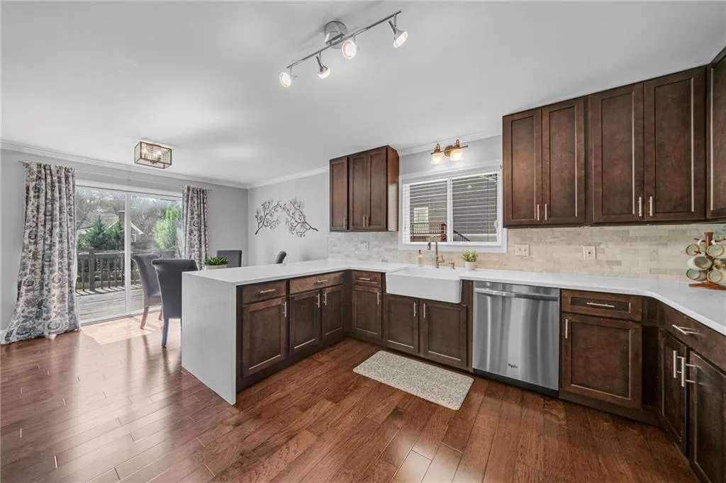 Kitchen featuring kitchen peninsula, dark hardwood / wood-style floors, dishwasher, sink, and tasteful backsplash