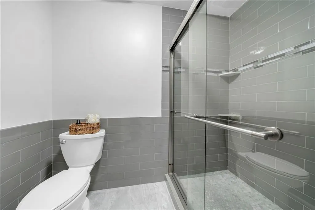 Bathroom with an enclosed shower, toilet, and tile walls