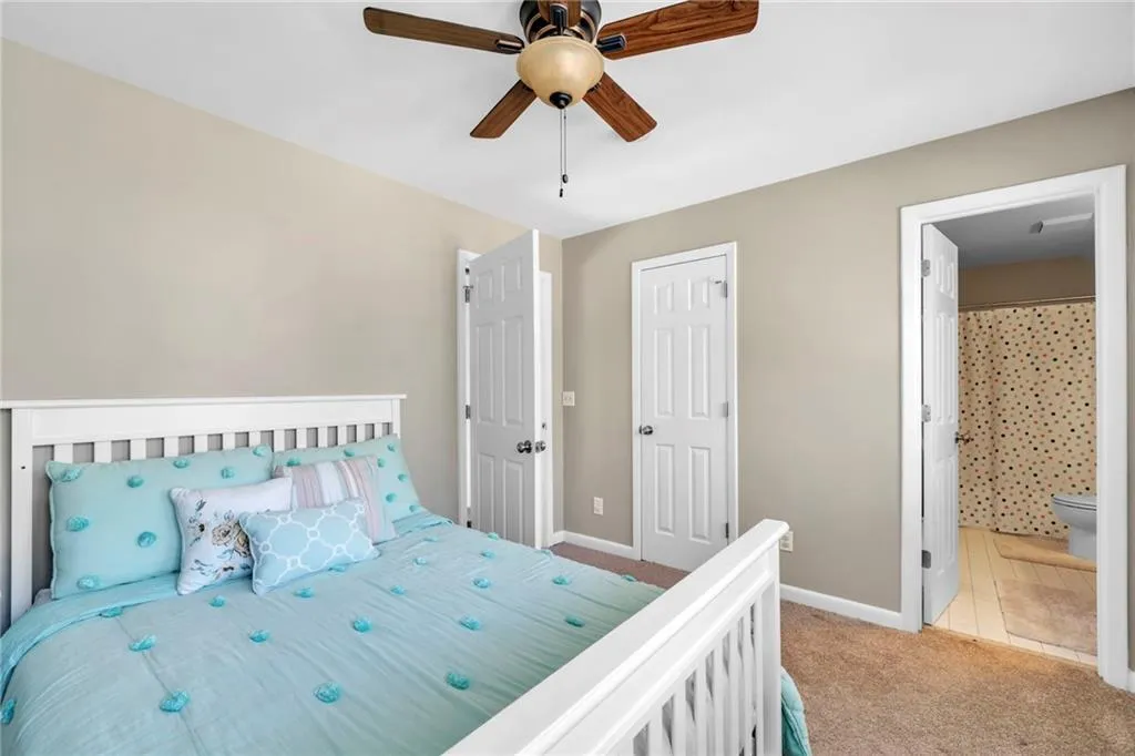 Bedroom featuring a closet, light carpet, connected bathroom, and ceiling fan