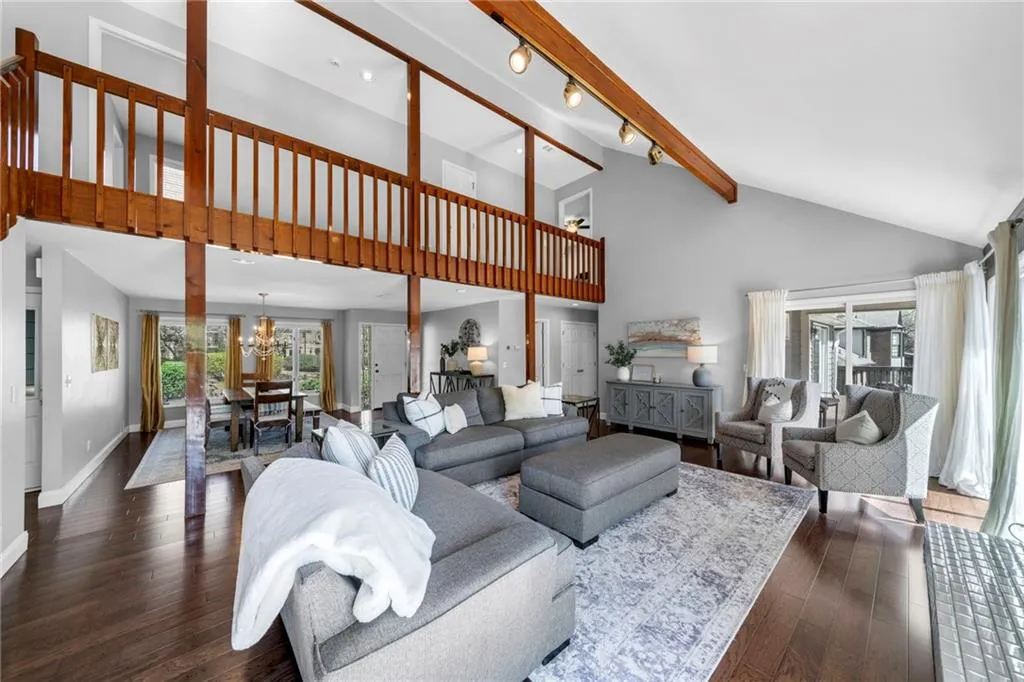 Living room featuring high vaulted ceiling, an inviting chandelier, beam ceiling, and dark wood-type flooring