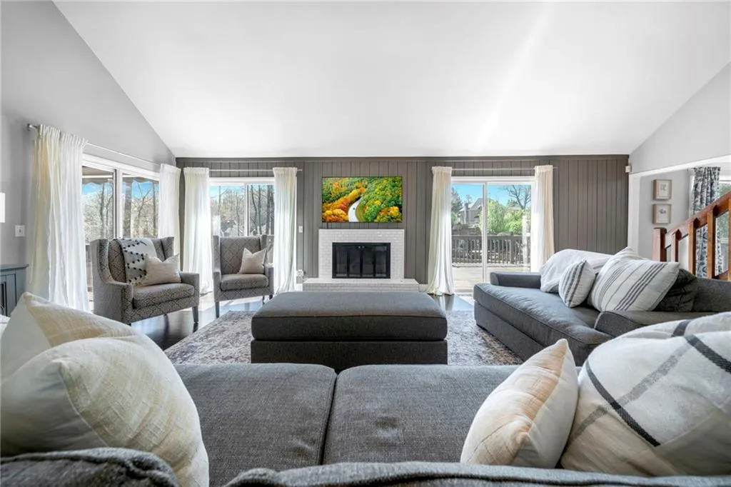 Living room featuring a fireplace, plenty of natural light, and high vaulted ceiling