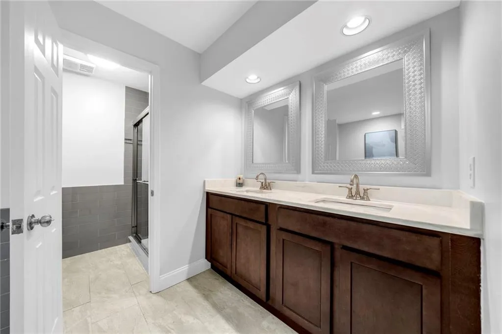 Bathroom featuring double sink vanity, a shower with door, and tile floors
