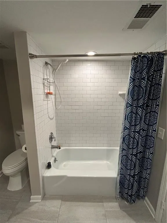 Full bath with shower / bath combo with shower curtain and light tile patterned flooring
