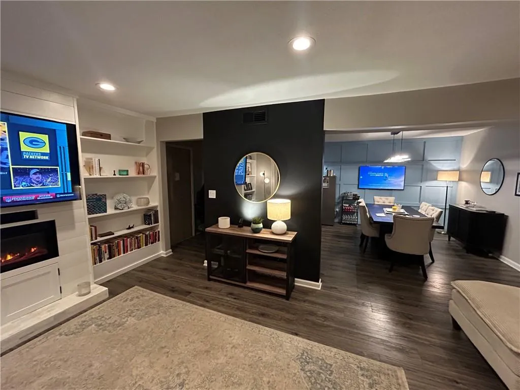 Living room with dark wood finished floors, recessed lighting, a fireplace, and built in features