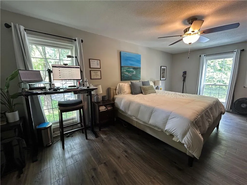Bedroom featuring dark wood finished floors, multiple windows, a textured ceiling, and ceiling fan
