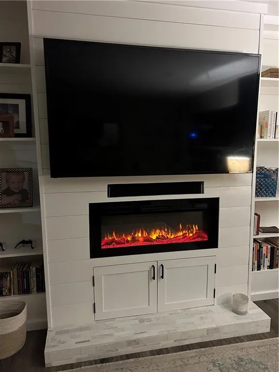 Detailed view of wood finished floors and a lit fireplace