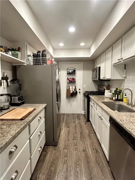 Kitchen featuring backsplash, light stone countertops, and white cabinets