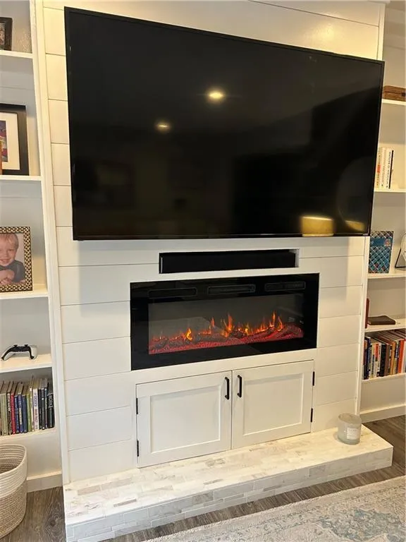 Living room featuring a glass covered fireplace, recessed lighting, and dark wood-style flooring