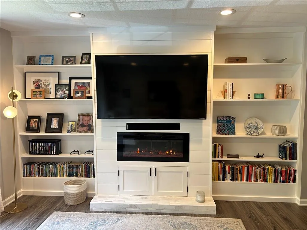 Living area featuring dark wood-style flooring, a fireplace, and recessed lighting