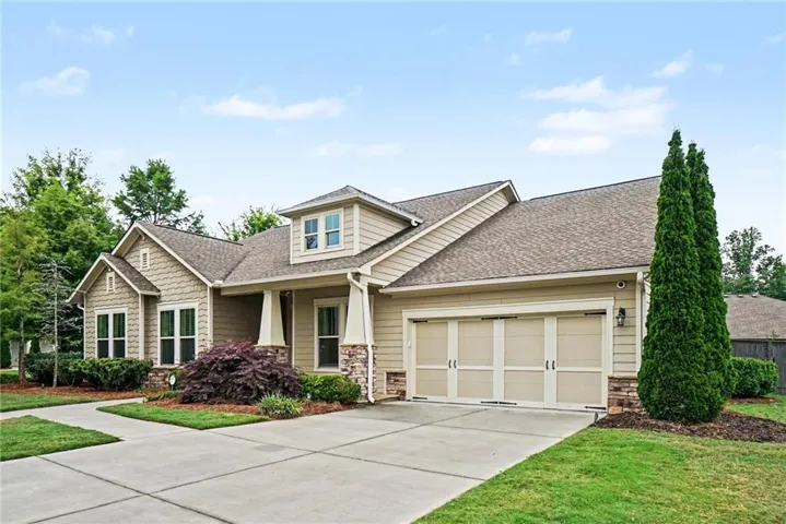 Craftsman-style exterior with stone veneer accents, dormer window, and an attached two-car garage