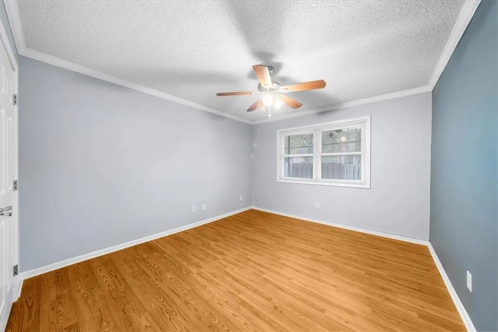 Unfurnished room with crown molding, light hardwood / wood-style floors, and a textured ceiling Unfurnished room with crown molding, light hardwood / wood-style floors, and a textured ceiling
