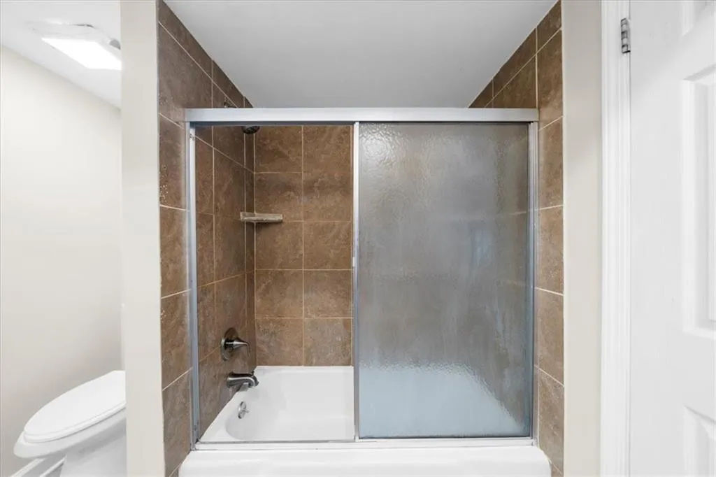 Bathroom with enclosed tub / shower combo and toilet Bathroom with enclosed tub / shower combo and toilet