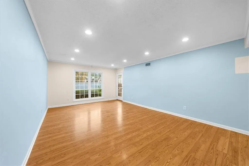 Empty room with a textured ceiling, crown molding, and light hardwood / wood-style flooring Empty room with a textured ceiling, crown molding, and light hardwood / wood-style flooring