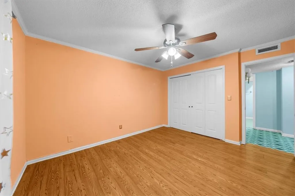 Unfurnished bedroom featuring a closet, ceiling fan, hardwood / wood-style floors, and a textured ceiling Unfurnished bedroom featuring a closet, ceiling fan, hardwood / wood-style floors, and a textured ceiling
