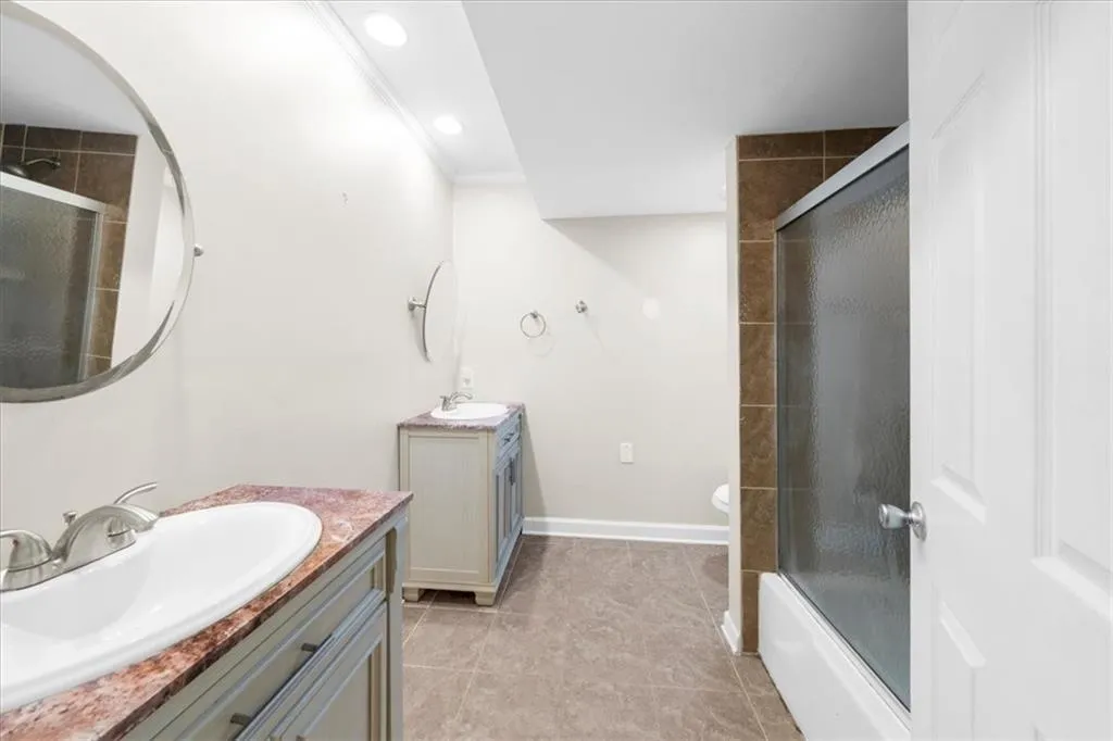 Full bathroom with vanity, crown molding, shower / bath combination with glass door, tile patterned flooring, and toilet Full bathroom with vanity, crown molding, shower / bath combination with glass door, tile patterned flooring, and toilet